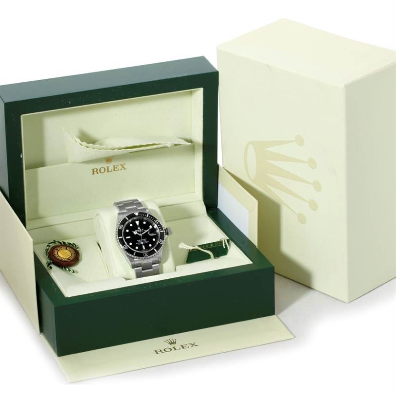 The image shows a Rolex Submariner 16610 Men
s Stainless Steel Black Dial 16610 Men
s Stainless Steel Black Dial watch from a front angle, presented in its box with accompanying accessories and tags.