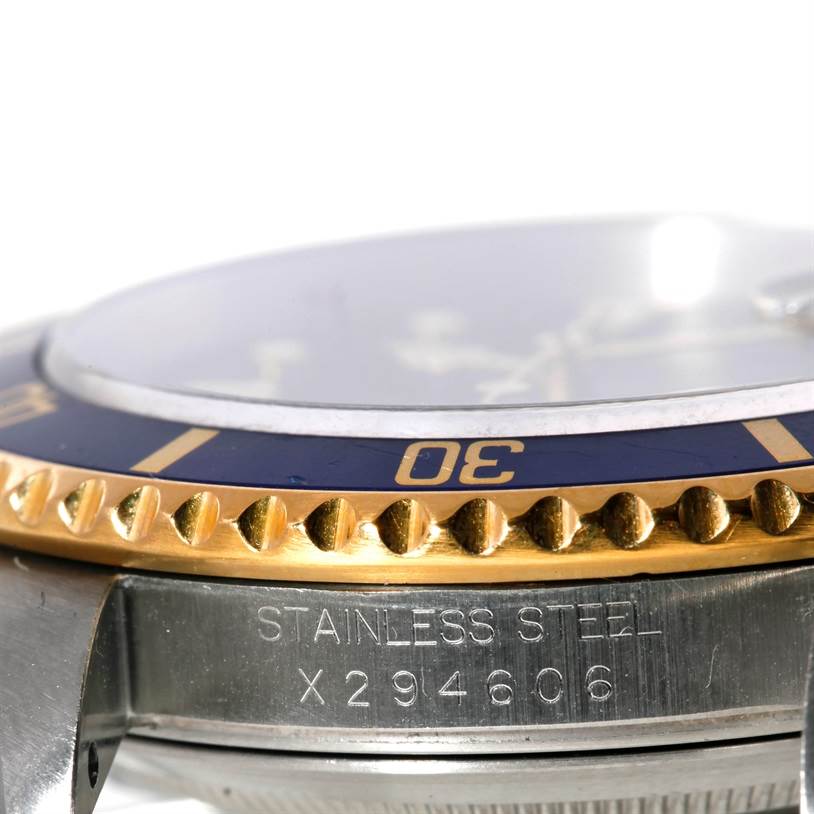 This image shows a close-up side view of a Rolex Submariner 16613 Men's Steel and Gold (two tone) Blue Dial 16613 Men's Steel and Gold (two tone) Blue Dial watch, highlighting the bezel, crystal, and part of the case with the serial number engraved.