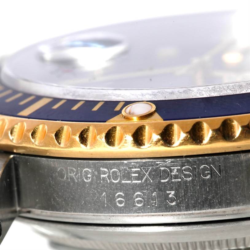This close-up image of the Rolex Submariner 16613 Men's Steel and Gold (two tone) Blue Dial 16613 Men's Steel and Gold (two tone) Blue Dial watch shows the side of the bezel and casing, revealing the "Orig Rolex Design" and model number 16613.