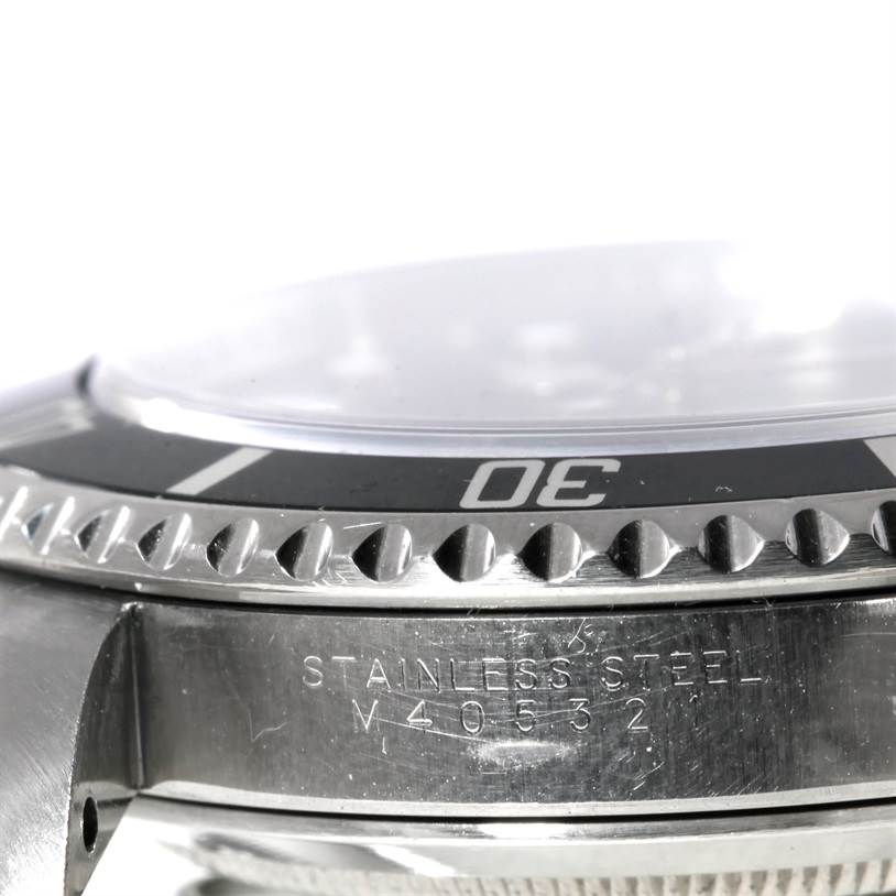 The image shows a close-up side angle of a Rolex Submariner 14060 Men
s Stainless Steel Black Dial 14060 Men
s Stainless Steel Black Dial watch, highlighting the bezel, crystal, and part of the stainless steel case with engravings.