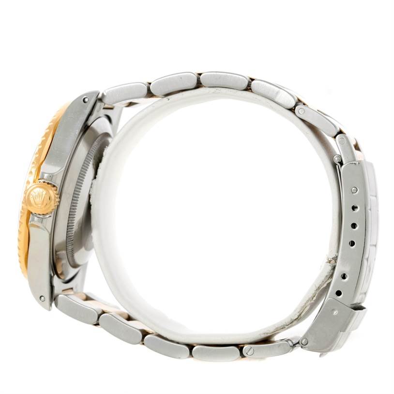 The image shows a side view of a Rolex Submariner 16803 Men's Steel and Gold (two tone) Black Dial 16803 Men's Steel and Gold (two tone) Black Dial watch, highlighting the crown, case, and metal bracelet.