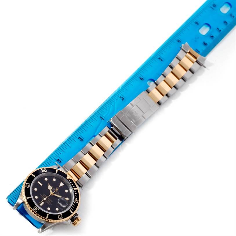 The image shows a Rolex Submariner 16803 Men's Steel and Gold (two tone) Black Dial 16803 Men's Steel and Gold (two tone) Black Dial watch laid flat with part of the bracelet measured by a ruler.