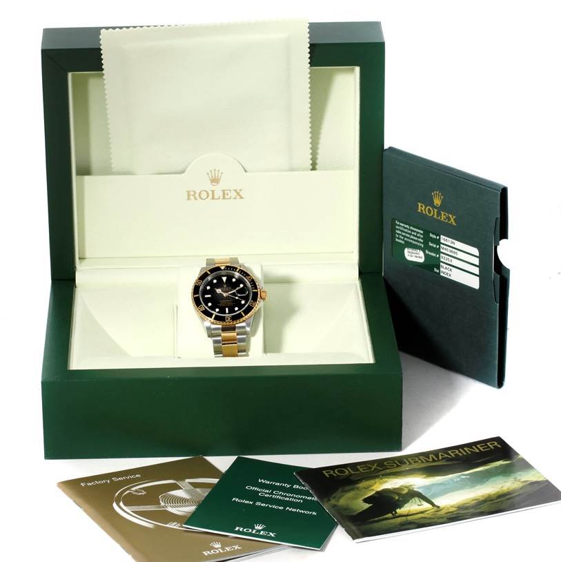 The image shows a front view of a Rolex Submariner 16613 Men's Steel and Gold (two tone) Black Dial 16613 Men's Steel and Gold (two tone) Black Dial watch in its box, with accompanying booklets and a cloth.