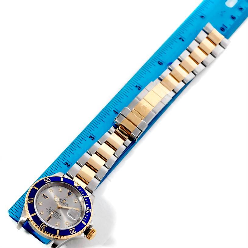 The image shows a Rolex Submariner 16613 Men's Steel and Gold (two tone) Grey Dial 16613 Men's Steel and Gold (two tone) Grey Dial watch laid flat with the watch band extended alongside a ruler.