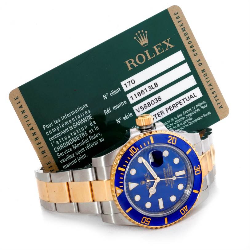 The image shows a Rolex Submariner 116613 Men's Steel and Gold (two tone) Blue Dial 116613 Men's Steel and Gold (two tone) Blue Dial watch with a blue and gold bezel, bracelet, and a service card in the background.