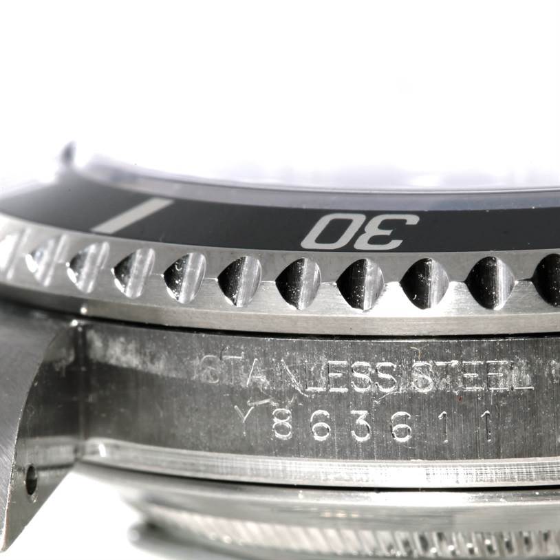 The image shows a close-up side view of a Rolex Submariner 16610 Men
s Stainless Steel Black Dial 16610 Men
s Stainless Steel Black Dial watch
s bezel and case, highlighting the serial number and part of the rotating bezel with minute markers.
