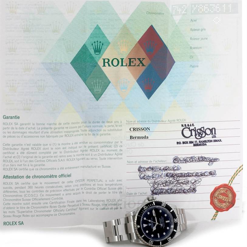 The image shows a Rolex Submariner 16610 Men
s Stainless Steel Black Dial 16610 Men
s Stainless Steel Black Dial watch from a frontal angle, placed on top of its warranty and documentation papers.
