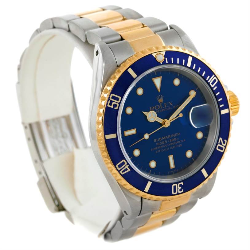 The image shows a Rolex Submariner 16613 Men's Steel and Gold (two tone) Blue Dial 16613 Men's Steel and Gold (two tone) Blue Dial watch from a three-quarter angle, highlighting its blue dial, bezel, and two-tone bracelet.