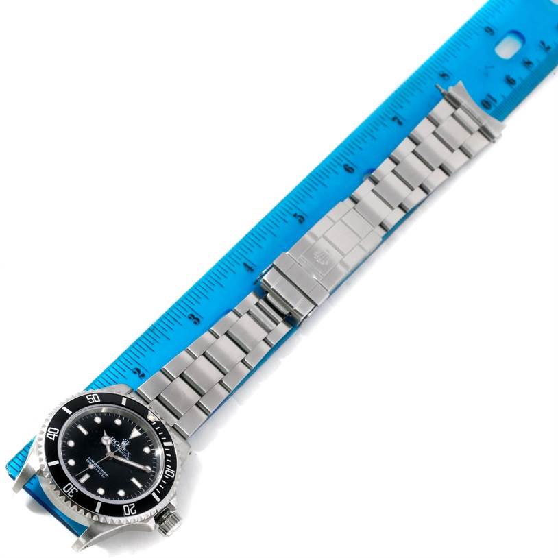 The Rolex Submariner 14060 Men
s Stainless Steel Black Dial 14060 Men
s Stainless Steel Black Dial watch is shown flat, with its face, bezel, and bracelet visible alongside a blue ruler.