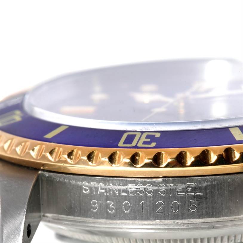 The image shows a close-up angle of the bezel, crystal, and part of the case of a Rolex Submariner 16803 Men's Steel and Gold (two tone) Blue Dial 16803 Men's Steel and Gold (two tone) Blue Dial watch.