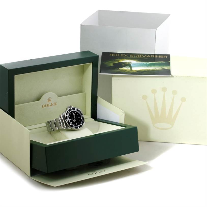 The image shows a Rolex Submariner 14060 Men
s Stainless Steel Black Dial 14060 Men
s Stainless Steel Black Dial watch at an angle inside its open green case, with accompanying packaging and user manual in the background.
