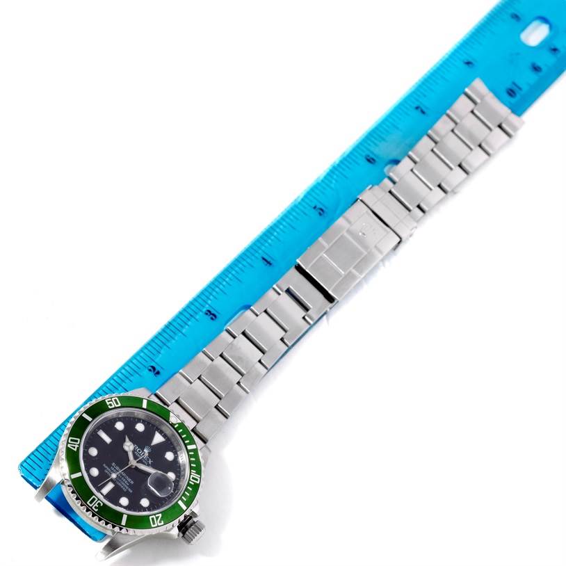 The image shows a full view of a Rolex Submariner 16610LV Men
s Stainless Steel Black Dial 16610LV Men
s Stainless Steel Black Dial watch, including the dial, bezel, and bracelet, next to a blue ruler.