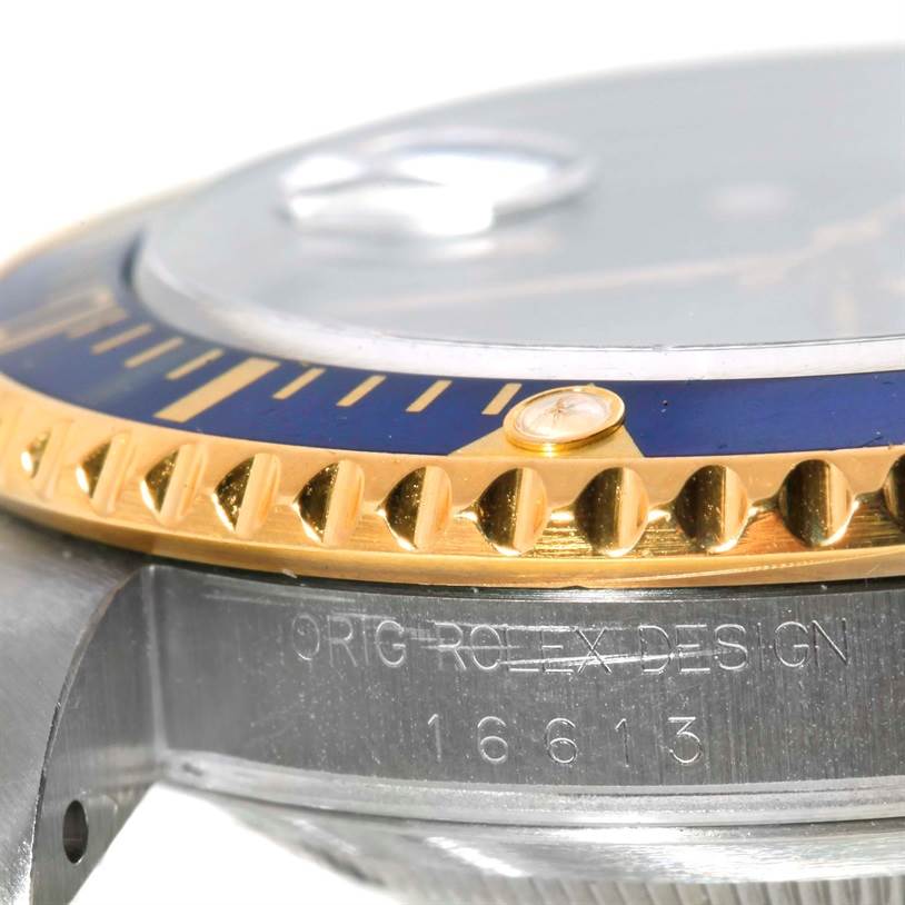 This image shows a close-up, angled view of the bezel and the side of the case of a Rolex Submariner 16613 Men's Steel and Gold (two tone) Blue Dial 16613 Men's Steel and Gold (two tone) Blue Dial model, focusing on the inscription and part of the dial.
