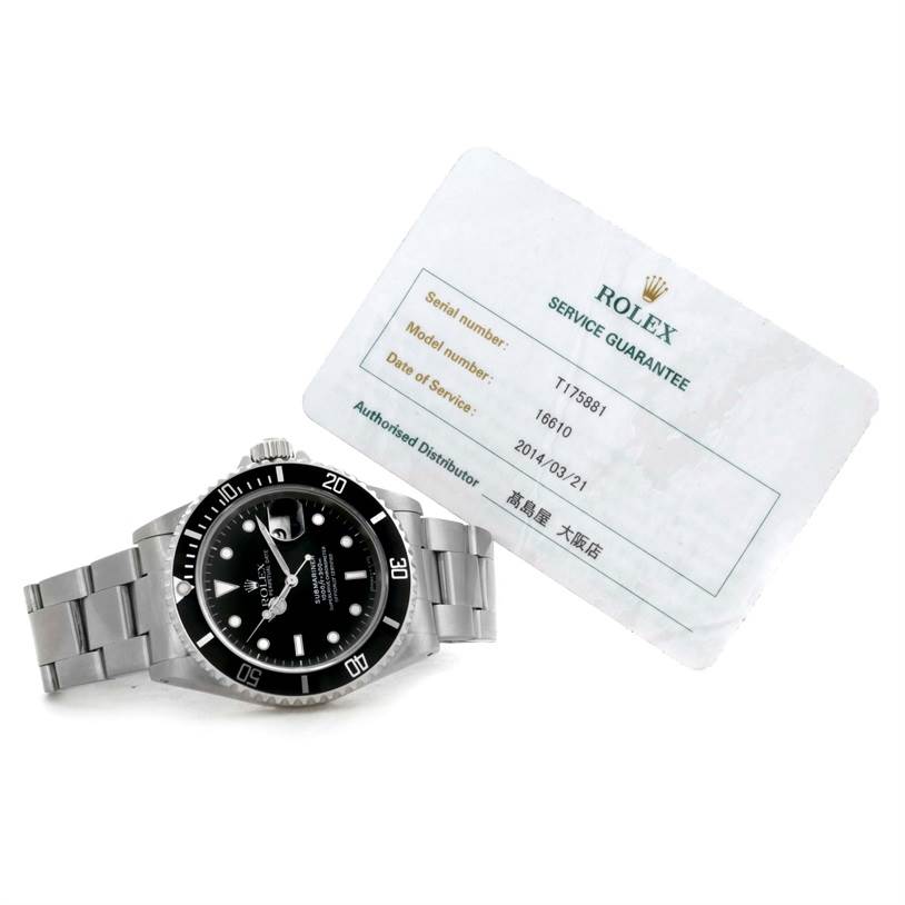 The image shows a Rolex Submariner 16610 Men
s Stainless Steel Black Dial 16610 Men
s Stainless Steel Black Dial watch at a slight angle, along with its service guarantee card.