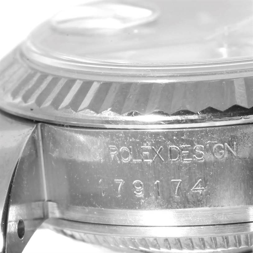 This close-up image of a Rolex Datejust 179174 Women
s Stainless Steel Silver Dial 179174 Women
s Stainless Steel Silver Dial watch shows part of the case, bezel, and crystal, with engraved model numbers visible.