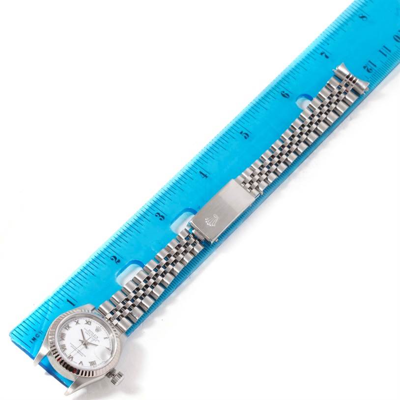 The watch is a Rolex Datejust 79174 Women's Stainless Steel White Dial 79174 Women's Stainless Steel White Dial model, shown at a straight angle with its face, bracelet, and clasp next to a ruler for measurement.