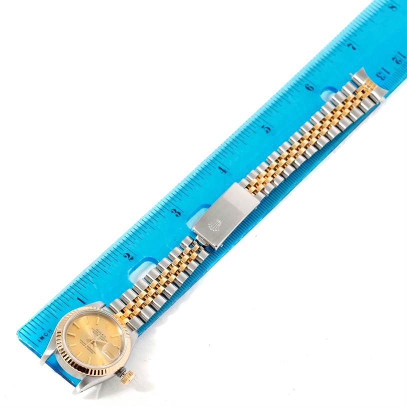 This image shows a Rolex Datejust 69173 Women's Stainless Steel Champagne Dial 69173 Women's Stainless Steel Champagne Dial watch laid flat next to a blue ruler, highlighting its band and face.