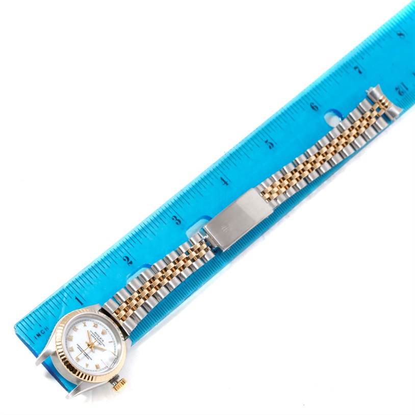 The image shows a Rolex Datejust 69173 Women
s Stainless Steel White Dial 69173 Women
s Stainless Steel White Dial watch lying flat next to a ruler, featuring its face, bezel, and bracelet.