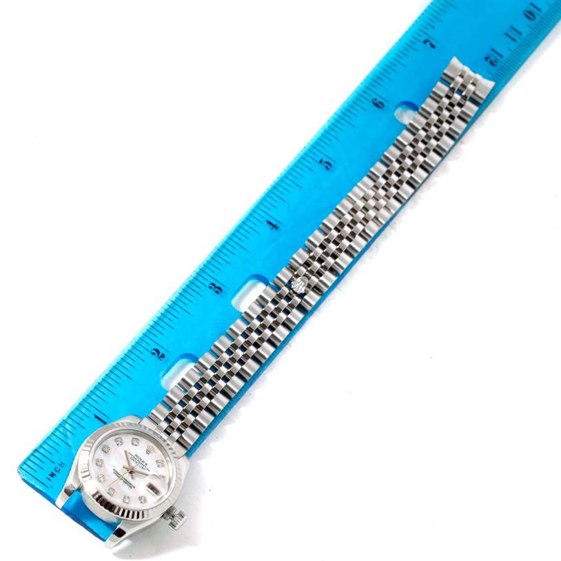 This image shows a Rolex Datejust 179174 Women's Stainless Steel Mother of Pearl Dial 179174 Women's Stainless Steel Mother of Pearl Dial watch laid beside a blue ruler, highlighting its face and bracelet.