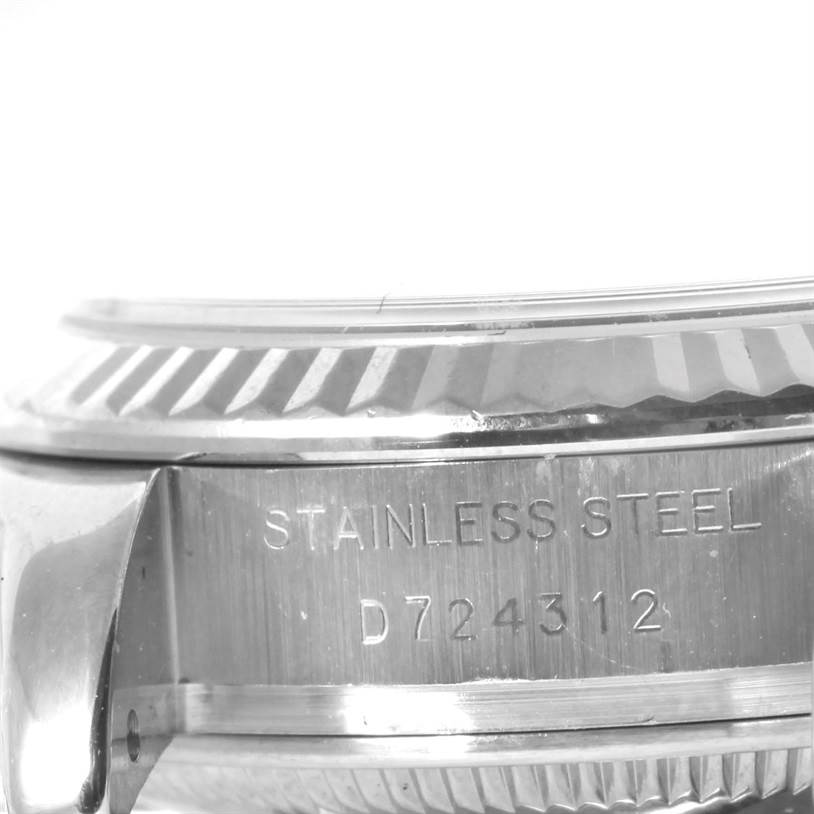 The image shows a close-up of the side case and fluted bezel of a Rolex Datejust 179174 Women's Stainless Steel Mother of Pearl Dial 179174 Women's Stainless Steel Mother of Pearl Dial model watch, highlighting its "Stainless Steel" marking and serial number.