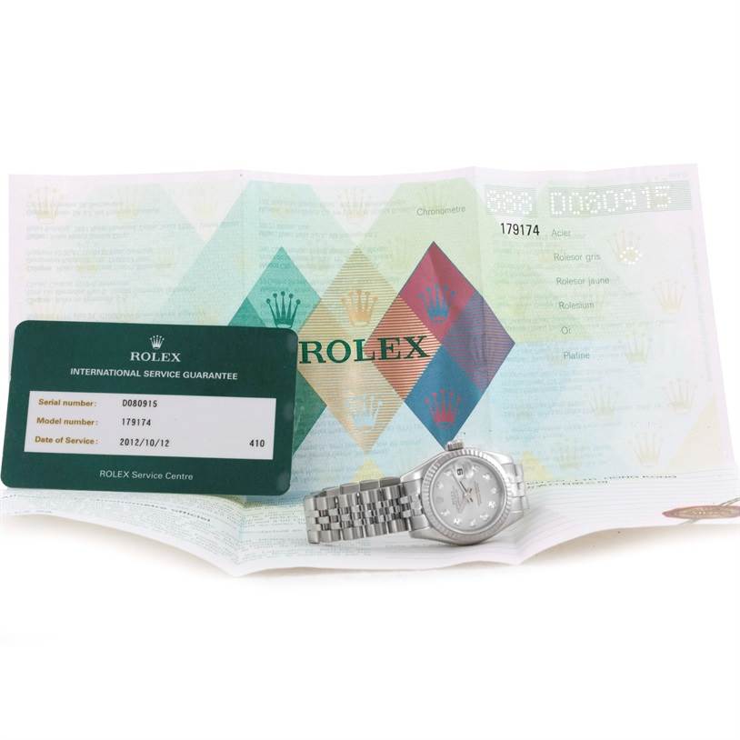 The image shows a Rolex Datejust 179174 Women
s Stainless Steel Silver Dial 179174 Women
s Stainless Steel Silver Dial watch, an international service guarantee card, and a document, all displayed from a top-down angle.