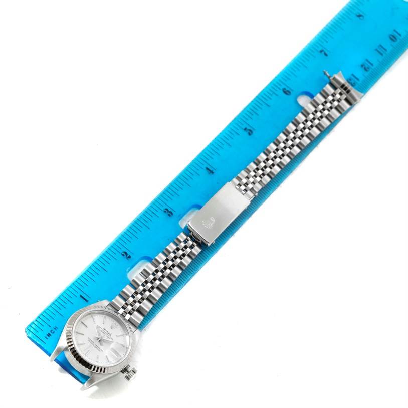 The Rolex Datejust 79174 Women
s Stainless Steel Silver Dial 79174 Women
s Stainless Steel Silver Dial watch is shown flat with its bracelet extended next to a blue ruler for measurement.