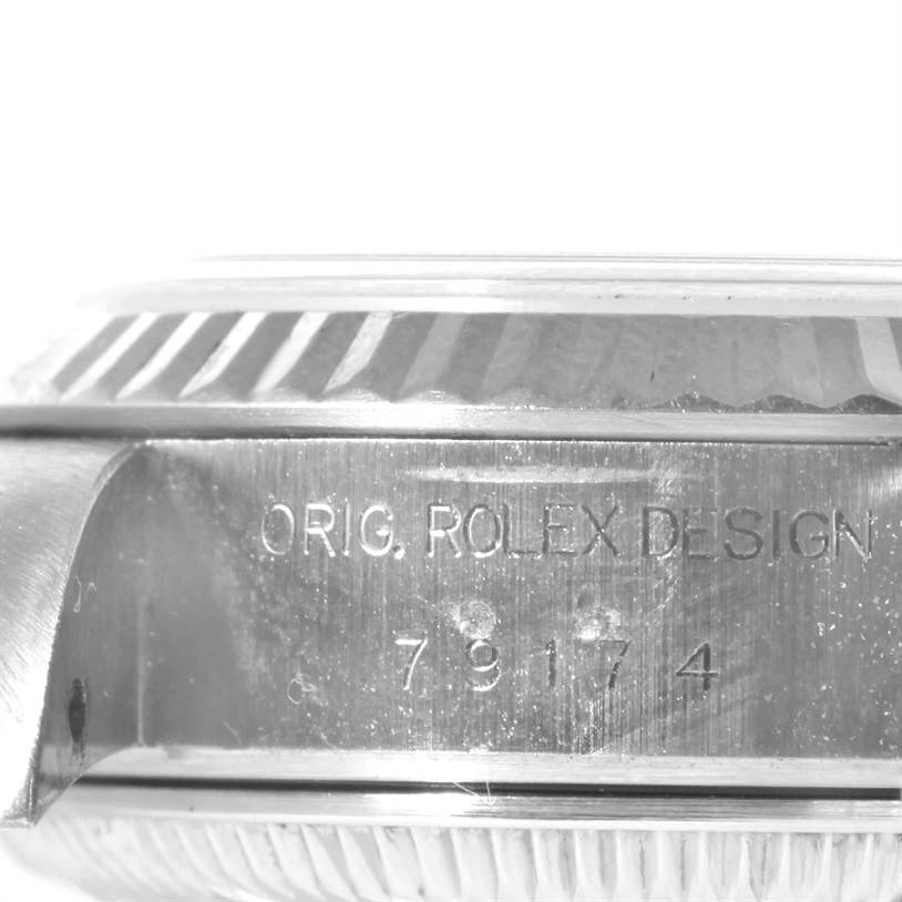 This image shows a close-up of the side of a Rolex Datejust 79174 Women
s Stainless Steel Silver Dial 79174 Women
s Stainless Steel Silver Dial watch with the engraving "ORIG. ROLEX DESIGN 79174".