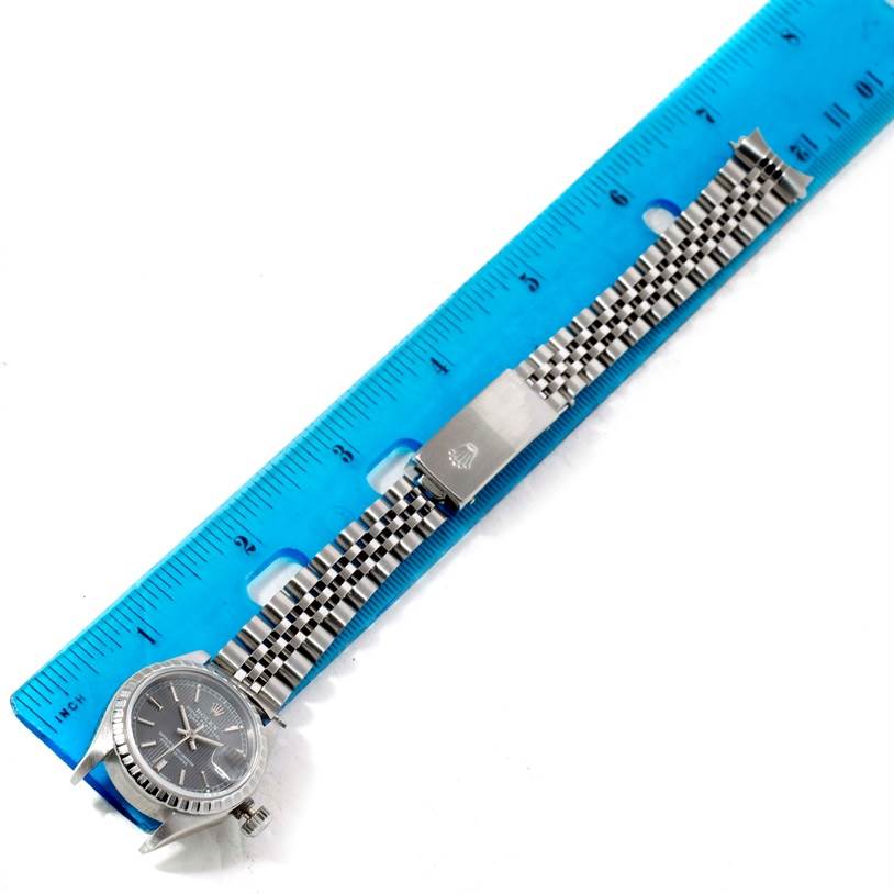 The Rolex Datejust 69240 Women's Stainless Steel Grey Dial 69240 Women's Stainless Steel Grey Dial watch is shown from a top-down angle, displaying the face, bezel, and full bracelet with a clasp against a blue ruler for scale.