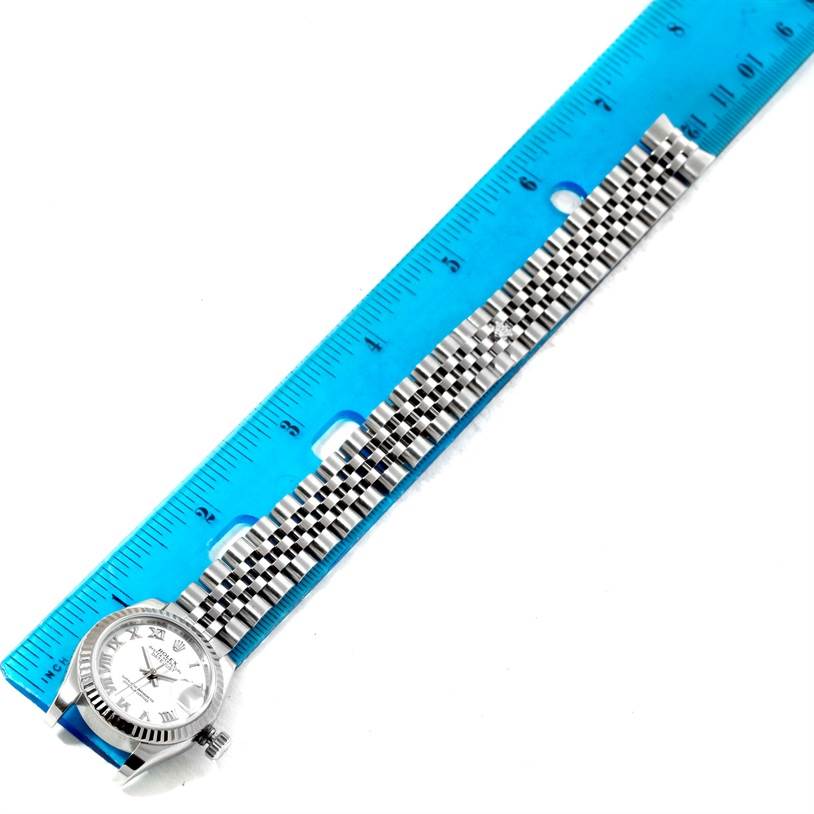 The Rolex Datejust 179174 Women's Stainless Steel White Dial 179174 Women's Stainless Steel White Dial watch is shown from a top-down angle, displaying the dial, bezel, and part of the bracelet next to a ruler.