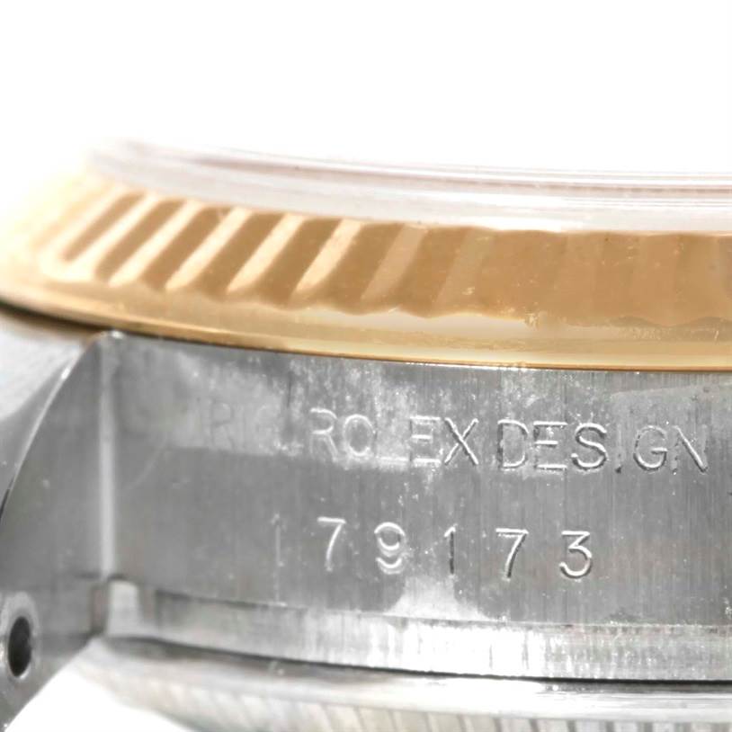 This close-up image shows the side of a Rolex Datejust 179173 Women's Steel and Gold (two tone) White Dial 179173 Women's Steel and Gold (two tone) White Dial watch, highlighting part of the bezel and the engraved model number.