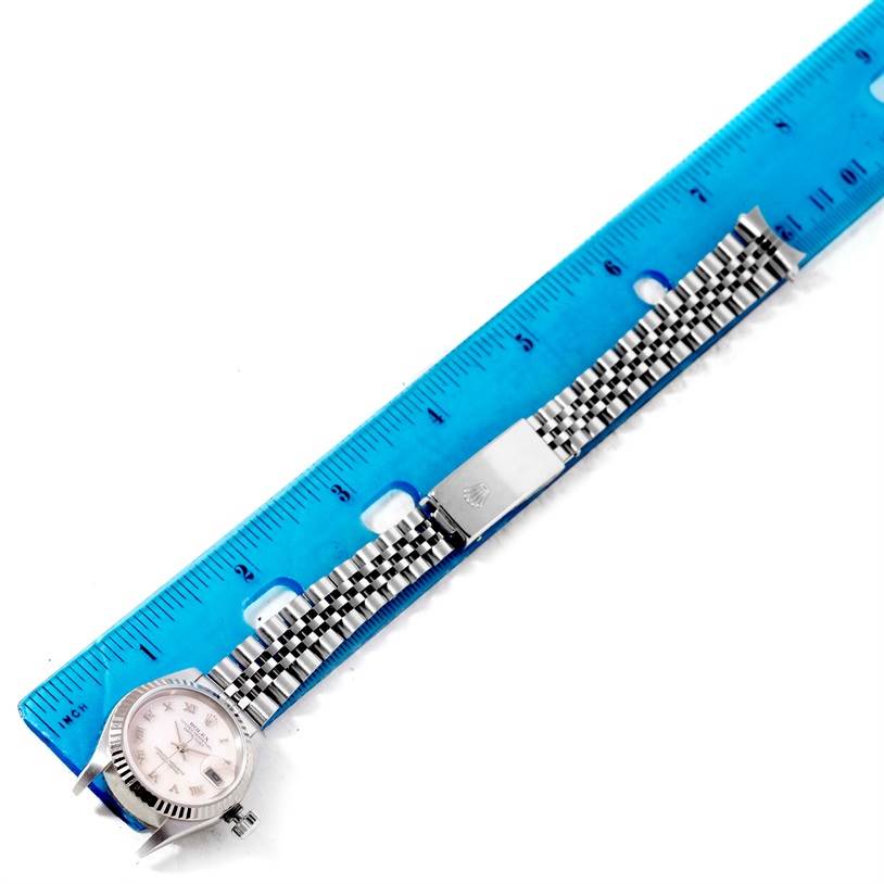 This image shows the side angle of a Rolex Datejust 79174 Women's Stainless Steel Mother of Pearl Dial 79174 Women's Stainless Steel Mother of Pearl Dial watch with its band and clasp, alongside a blue ruler for measurement.