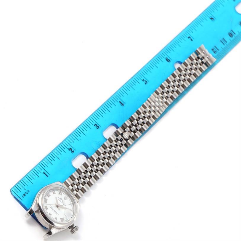 The image shows a Rolex Datejust 179160 Women's Stainless Steel White Dial 179160 Women's Stainless Steel White Dial watch from the top angle, placed next to a blue ruler with its face and bracelet visible.