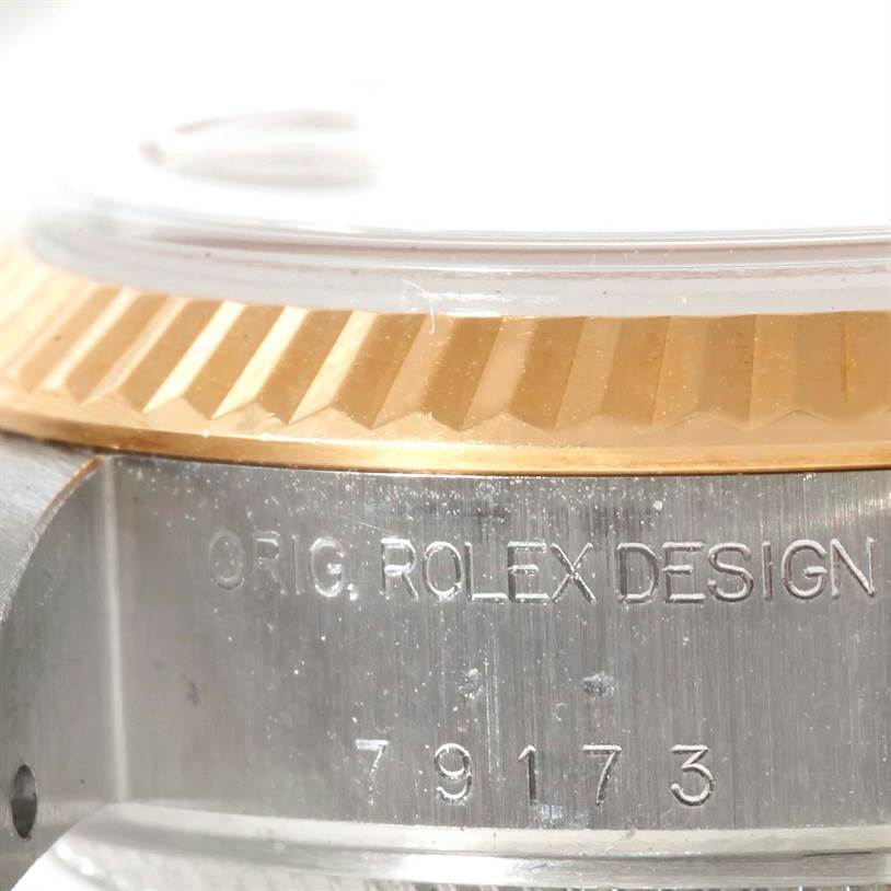 This close-up image of the Rolex Datejust 79163 Women's Steel and Gold (two tone) Pink Dial 79163 Women's Steel and Gold (two tone) Pink Dial model shows the side of the watch case, bezel, and the engraved model number.
