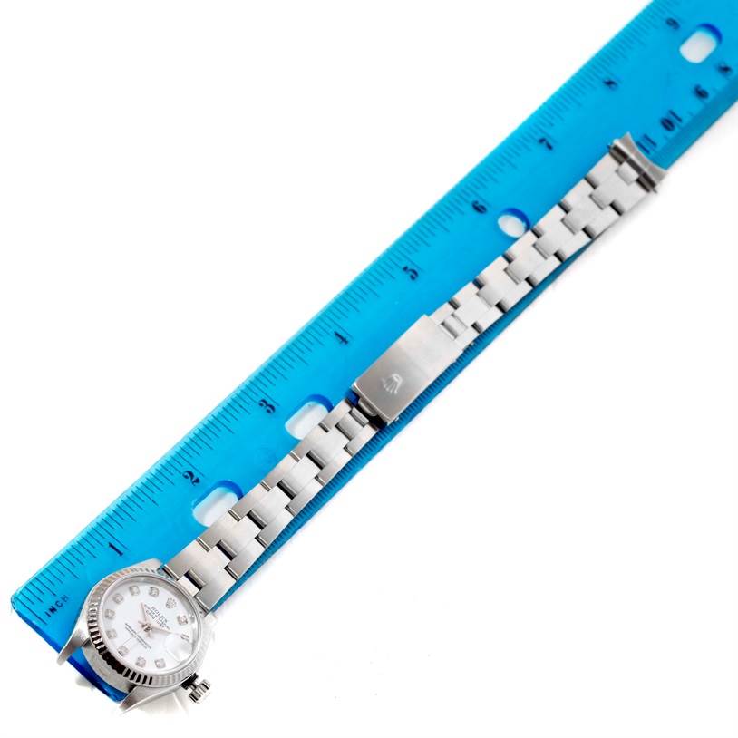 The image shows a Rolex Datejust 79174 Women's Stainless Steel White Dial 79174 Women's Stainless Steel White Dial watch laying flat alongside a blue ruler, showcasing its bracelet and clasp.