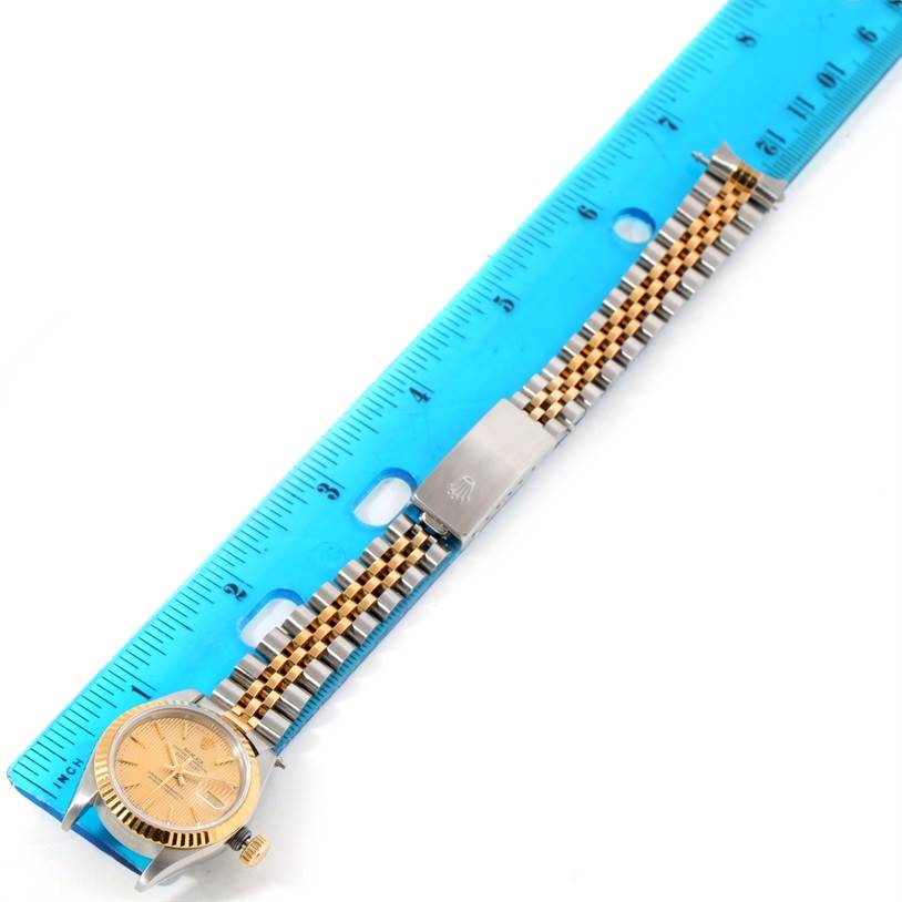 The image shows a Rolex Datejust 69173 Women's Stainless Steel Champagne Dial 69173 Women's Stainless Steel Champagne Dial watch laid on a blue ruler, highlighting the face, band, and clasp from a top-down angle.