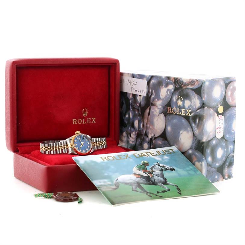 The Rolex Datejust 69173 Women
s Stainless Steel Blue Dial 69173 Women
s Stainless Steel Blue Dial watch is shown in a red box with its booklet, outer case, and accessories at a straight-on angle.