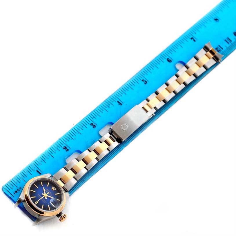 The image shows a Rolex Datejust 79163 Women
s Steel and Gold (two tone) Blue Dial 79163 Women
s Steel and Gold (two tone) Blue Dial watch laid flat with a blue ruler, highlighting the bracelet and clasp.