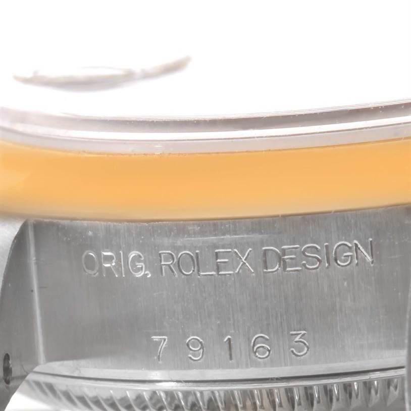 The image shows a close-up angle of the side of a Rolex Datejust 79163 Women
s Steel and Gold (two tone) Blue Dial 79163 Women
s Steel and Gold (two tone) Blue Dial watch case, featuring the model number 79163 and "ORIG. ROLEX DESIGN."