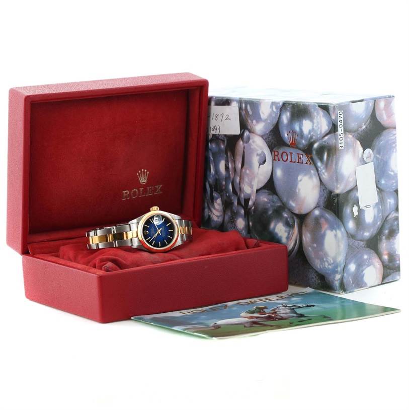 The image shows a Rolex Datejust 79163 Women
s Steel and Gold (two tone) Blue Dial 79163 Women
s Steel and Gold (two tone) Blue Dial watch inside its red box, alongside the packaging box and a booklet.