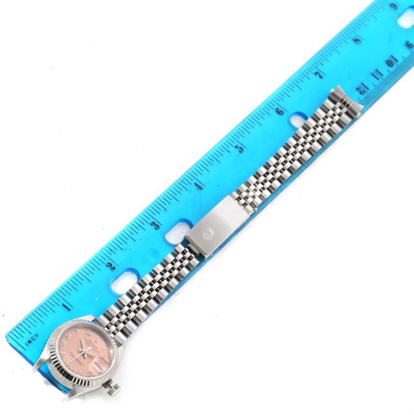 The image shows a Rolex Datejust 69174 Women
s Stainless Steel Pink Dial 69174 Women
s Stainless Steel Pink Dial watch laid flat alongside a blue ruler, displaying the watch face and complete bracelet.