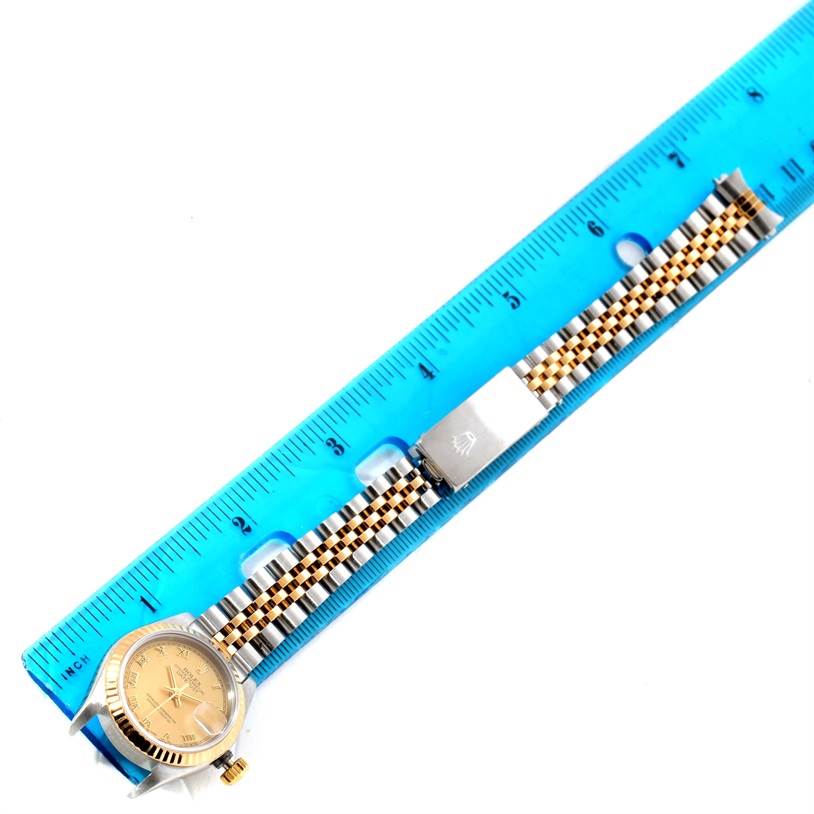 The Rolex Datejust 69173 Women's Stainless Steel Champagne Dial 69173 Women's Stainless Steel Champagne Dial watch is shown from an overhead angle, displaying its dial, bezel, and two-tone bracelet next to a ruler.