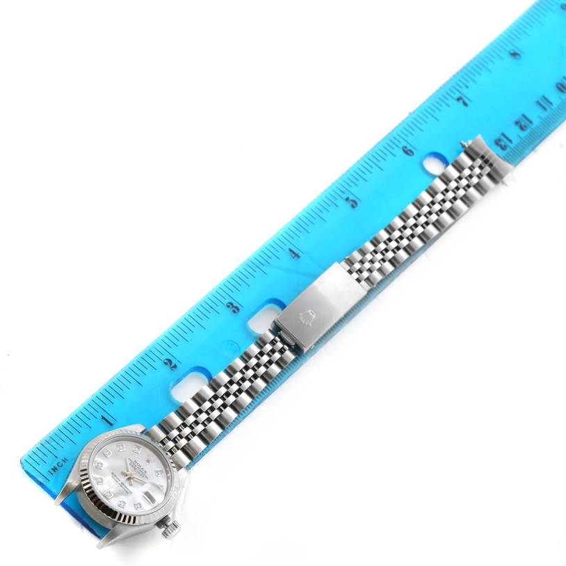 The image shows a Rolex Datejust 79174 Women
s Stainless Steel Mother of Pearl Dial 79174 Women
s Stainless Steel Mother of Pearl Dial watch face and bracelet alongside a blue ruler, photographed from a top-down angle.