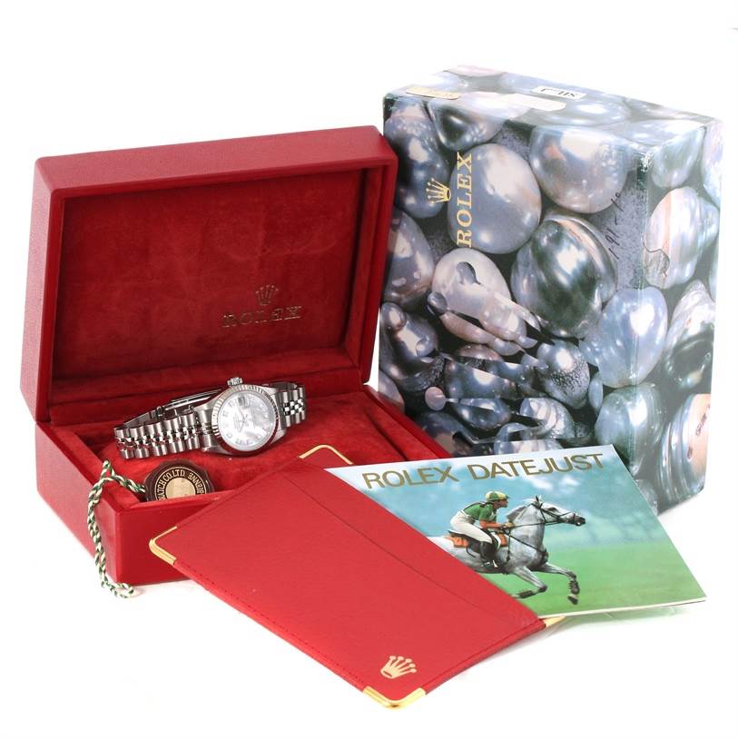 The image shows a Rolex Datejust 79174 Women
s Stainless Steel Mother of Pearl Dial 79174 Women
s Stainless Steel Mother of Pearl Dial watch inside its open box, accompanied by a booklet and packaging.