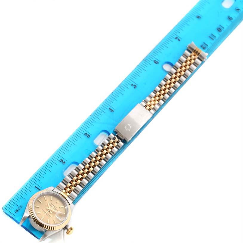 The Rolex Datejust 69173 Women's Stainless Steel Champagne Dial 69173 Women's Stainless Steel Champagne Dial watch is shown from a top-down angle, displaying the face, crown, and bracelet fully extended along a ruler.