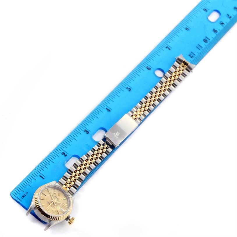 The Rolex Datejust 69173 Women's Stainless Steel Champagne Dial 69173 Women's Stainless Steel Champagne Dial watch is viewed from the top, showing the face, bezel, and full bracelet with a blue ruler for scale.