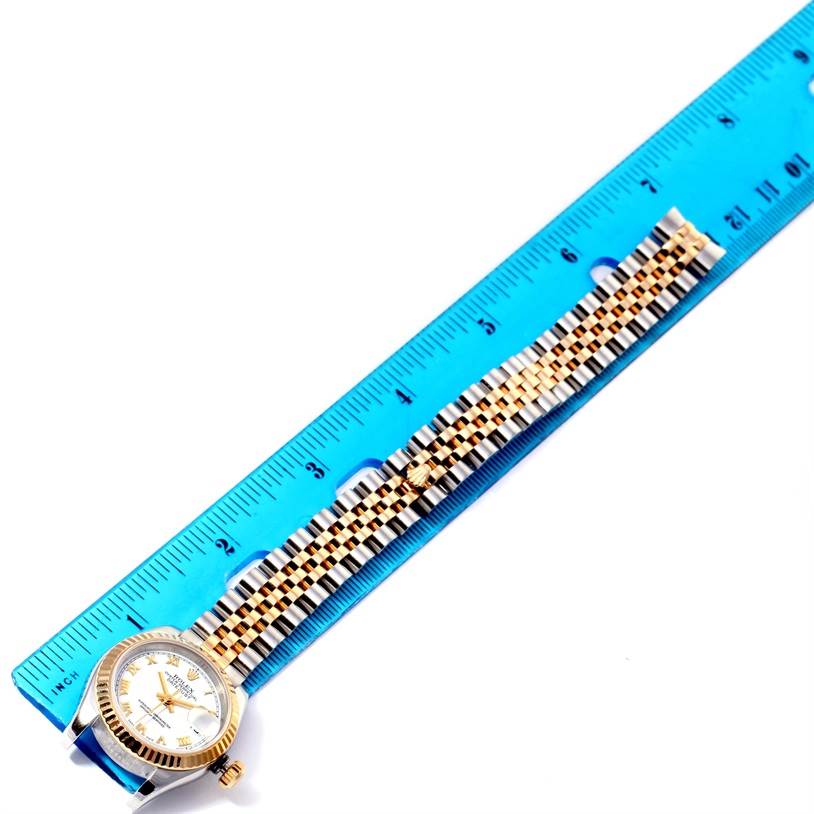 The image shows a Rolex Datejust 179173 Women's Steel and Gold (two tone) White Dial 179173 Women's Steel and Gold (two tone) White Dial watch lying flat next to a ruler, showcasing its case, dial, and bracelet.