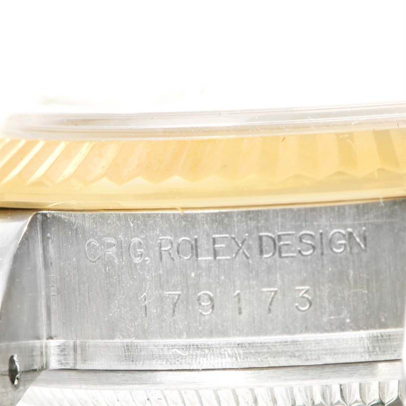 This close-up shows the engraving with the model number on the side of the Rolex Datejust 179173 Women's Steel and Gold (two tone) White Dial 179173 Women's Steel and Gold (two tone) White Dial case, including a partial view of the bezel.