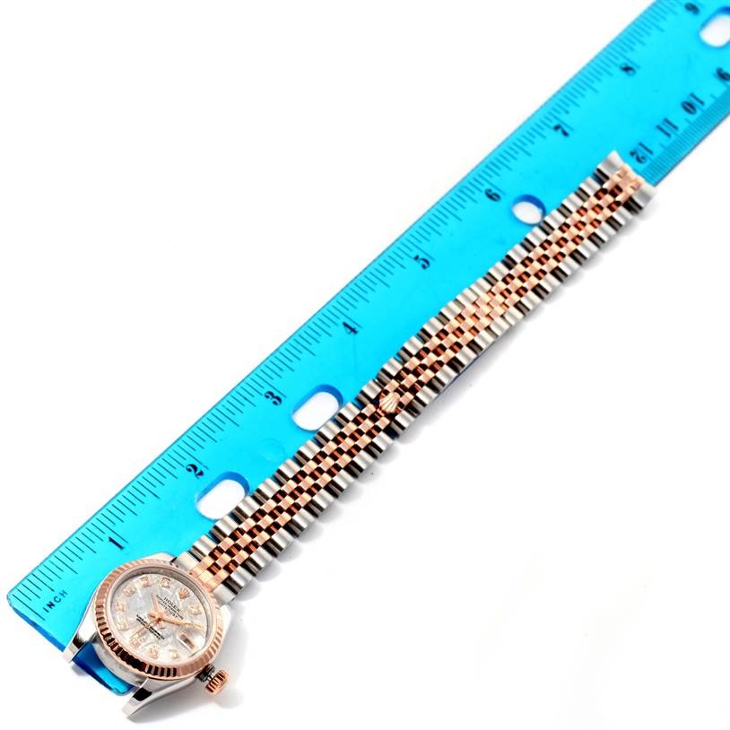 The image shows a Rolex Datejust 179171 Women
s Steel and Gold (two tone) Silver Dial 179171 Women
s Steel and Gold (two tone) Silver Dial watch lying flat next to a blue ruler, showcasing its bracelet and face.