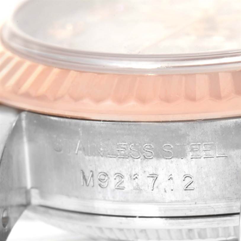 The image shows a close-up angle of the side of a Rolex Datejust 179171 Women
s Steel and Gold (two tone) Silver Dial 179171 Women
s Steel and Gold (two tone) Silver Dial watch focusing on the fluted bezel and engraved serial number.