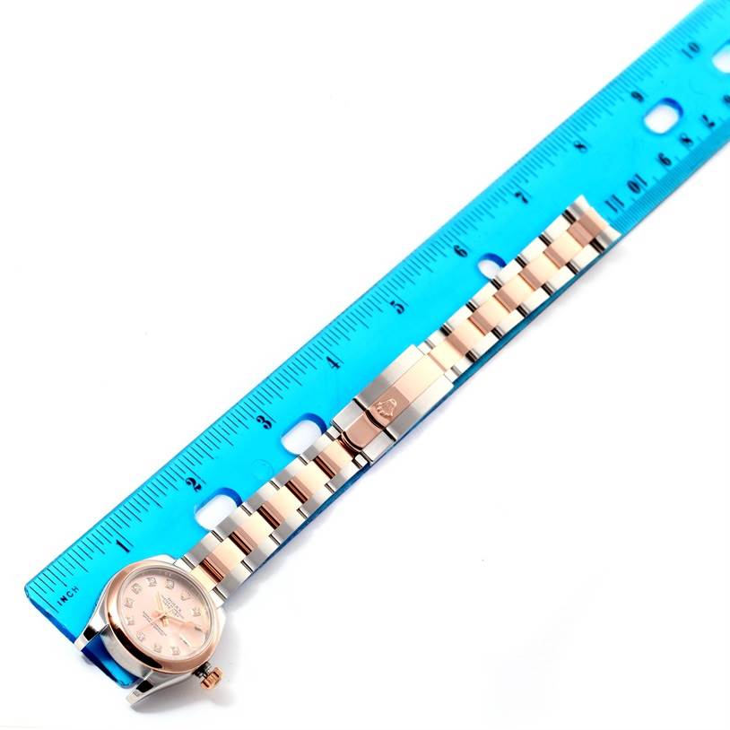 The image shows a Rolex Datejust 179161PDO Women's Steel and Gold (two tone) Pink Dial 179161PDO Women's Steel and Gold (two tone) Pink Dial watch laid flat with its bracelet measured against a blue ruler.